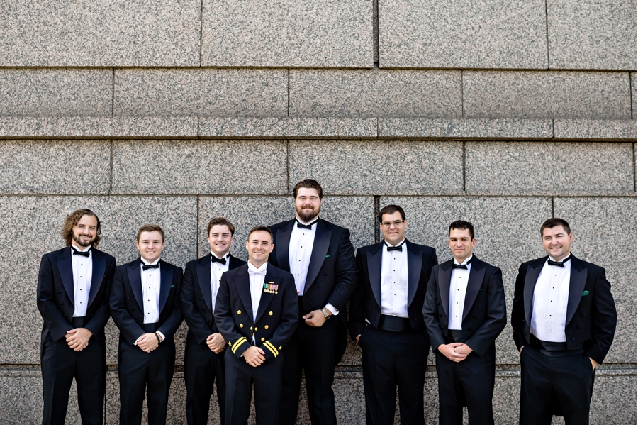 A groom in his Navy uniform with his groomsmen in their tuxes